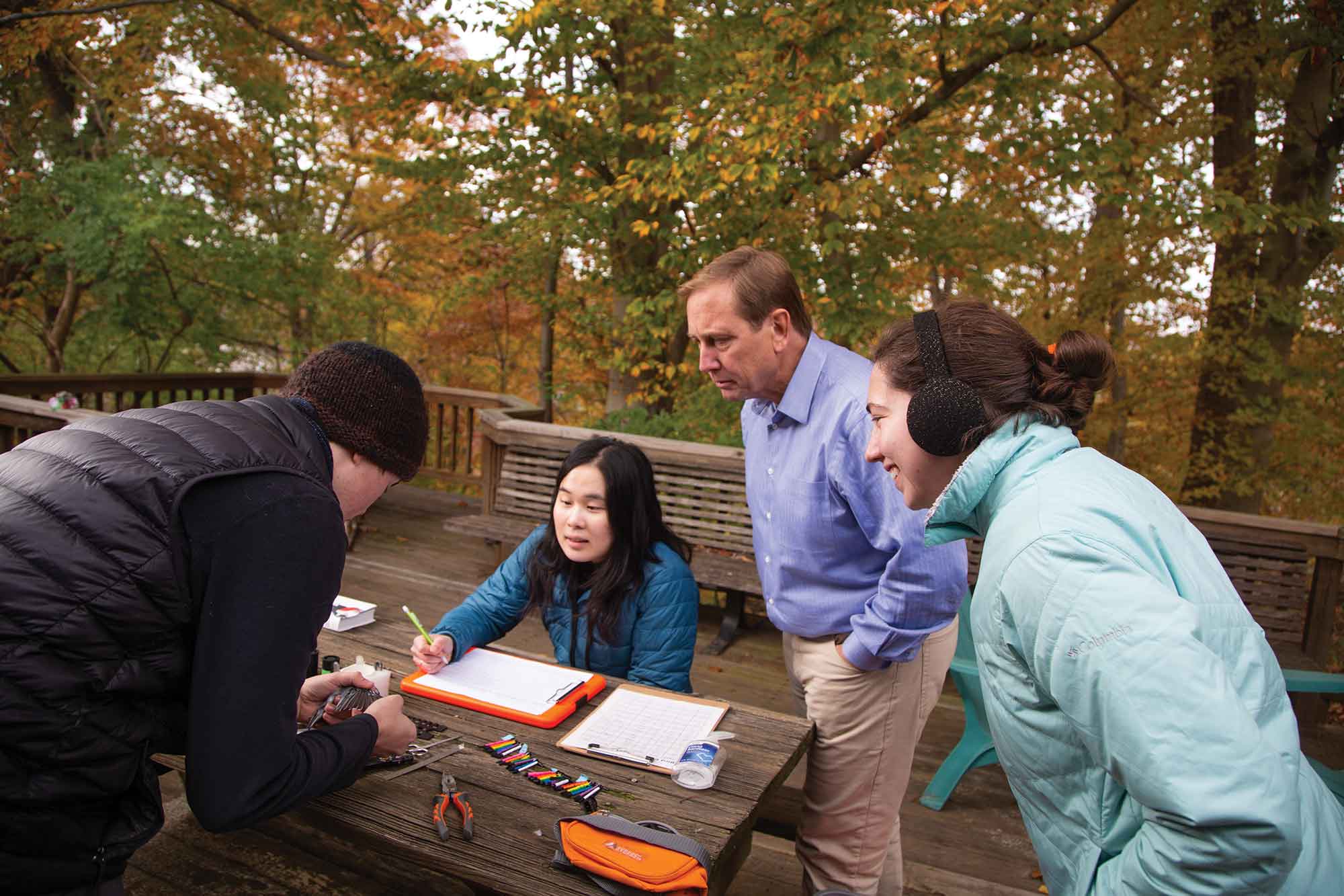 SCSU alumnus Peter Marra, '85, with students observing bird, writing in journal