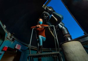 a student prepares to use the telescope inside the campus observatory