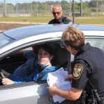 a police officer speaks to a driver behind the wheel of a car