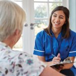 a young woman in scrubs talks to an elderly patient