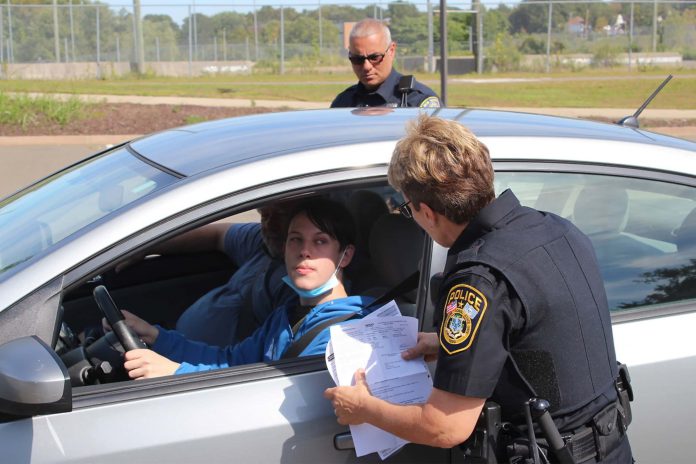 a police officer speaks to a driver behind the wheel of a car