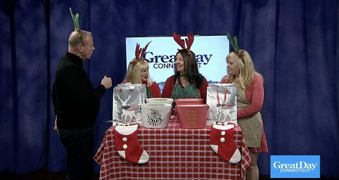 Four people with Christmas outfits on in front of television that say Great Day Connecticut