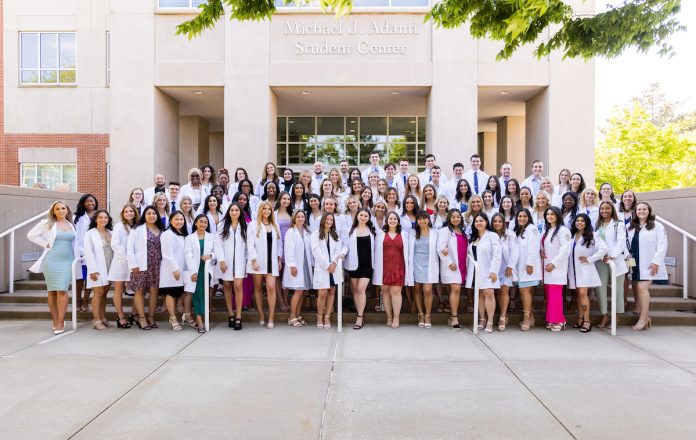 nursing students pose in their white jackets