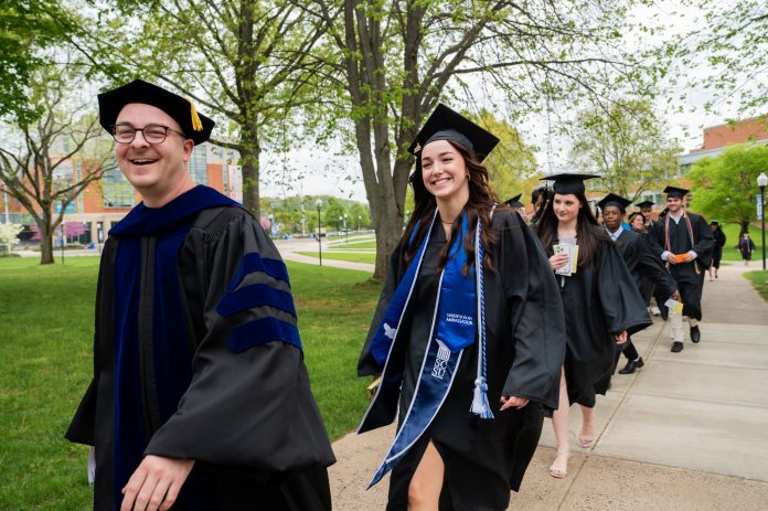 Students in caps and gowns walking and smiling
