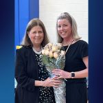 Superintendent Susan Compton presents a bouquet of roses to Jessica DeNigris, who smiles while holding the flowers after being named Educator of the Year.