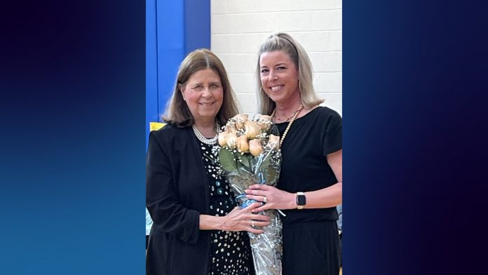 Superintendent Susan Compton presents a bouquet of roses to Jessica DeNigris, who smiles while holding the flowers after being named Educator of the Year.
