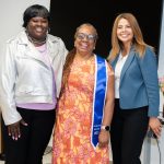 Three women, the middle a recent graduate wearing a stole.