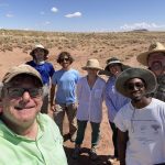 A group self with an expanse of brown ground and sky in the background.