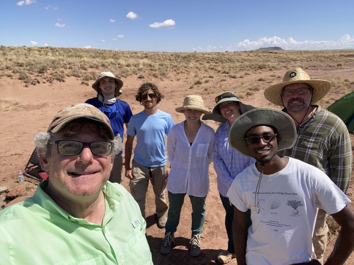 A group self with an expanse of brown ground and sky in the background.