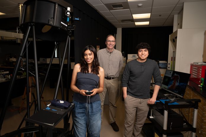 The team of Ana Baculima, '25; Elliott Horch, Connecticut State University Professor of Physics; and Sebastian Lucero, '25, stand in the Astronomy Lab, surrounded by various pieces of equipment.